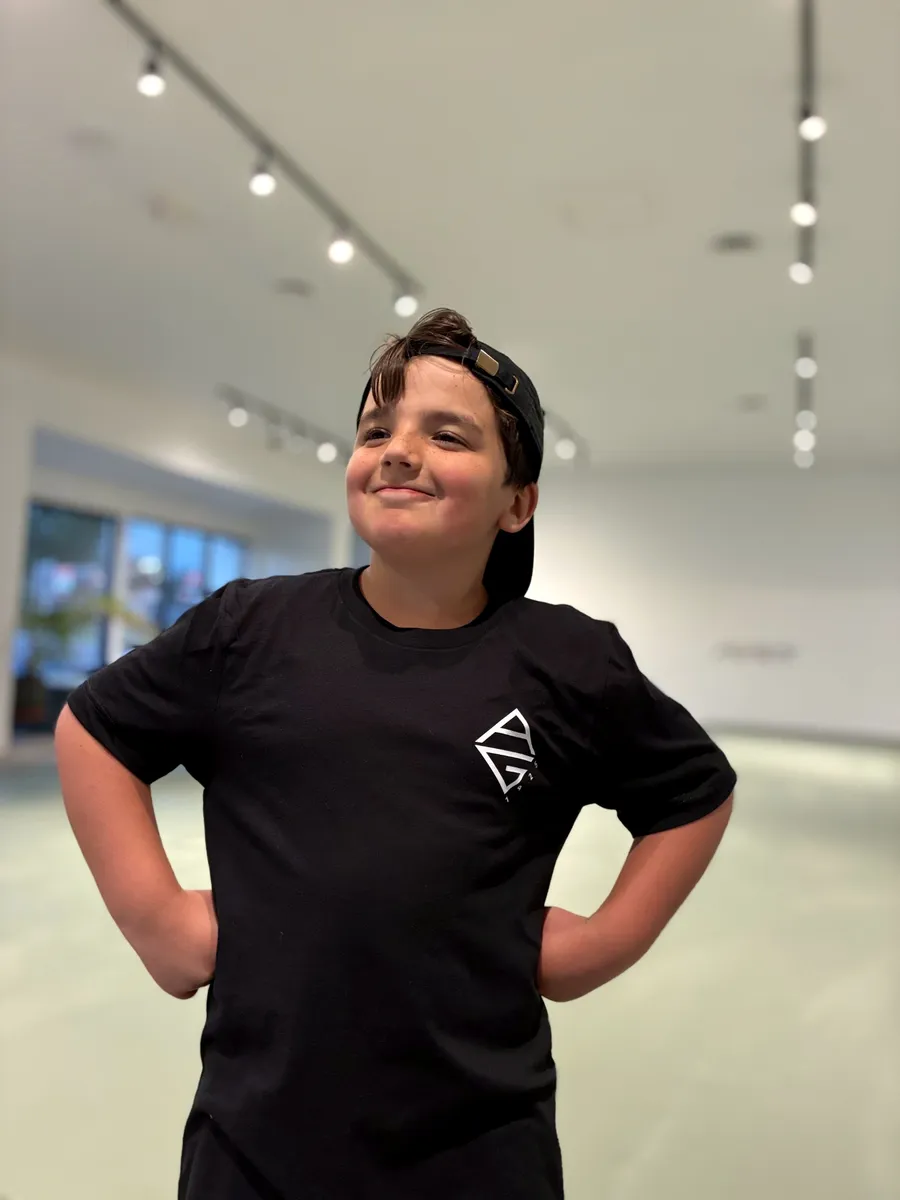A young student smiling in the AG1925 tee