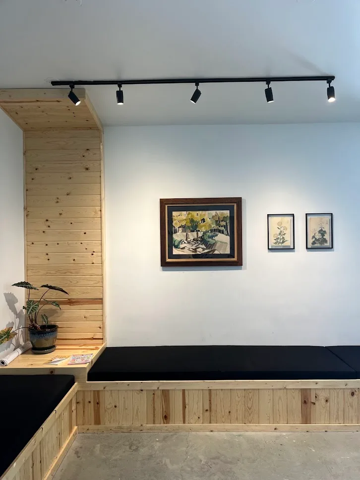 The academy lounge: wood benches, a plant and framed art