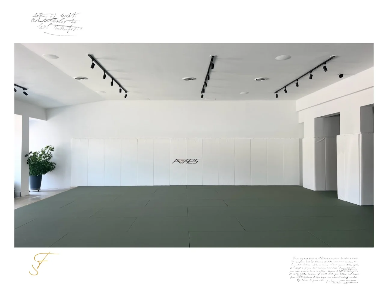 The empty AG1925 mat room, framed with handwritten script and a gold monogram